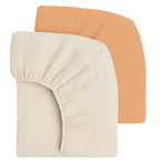 Two fitted crib sheets, one sand and one peach, on a white background.