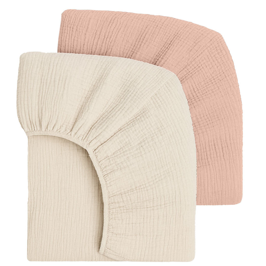 Two fitted crib sheets, one cream and one pink, on a white background.