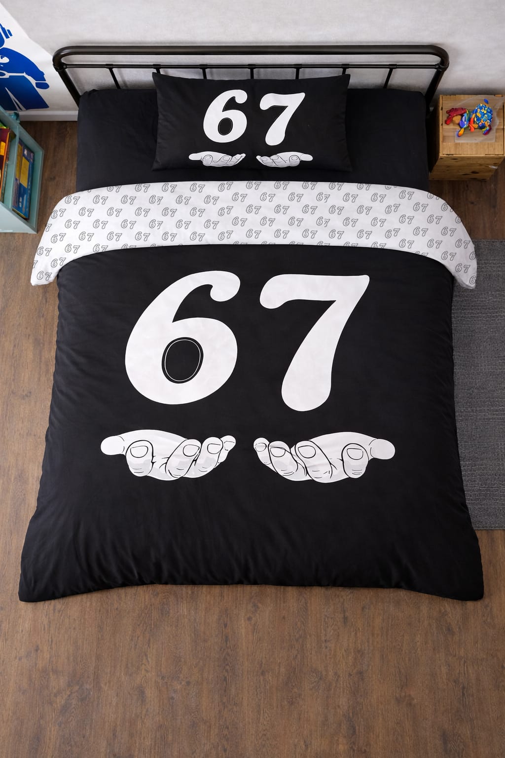 Top-down view of 6-7 twin duvet cover set on bed, black comforter with large white 67 number and hands graphic